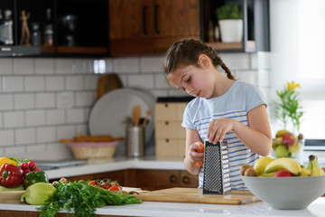 Young pretty girl helping in the kitchen preparing a healthy vegetarian meal