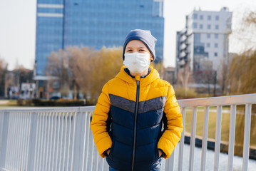Obraz premium A boy stands on a gray background in a mask during a quarantine with free space. Quarantine in the mask