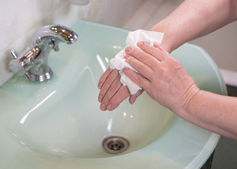 Woman using antibacterial wipes to disinfect her hands close up