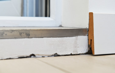 Poor decoration of the threshold of ceramic tiles. MDF skirting board is poorly installed, uneven cut. The transition between the floor and the threshold.
