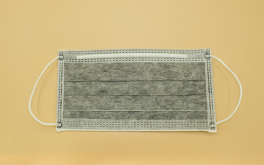 single carbon charcoal paper mask surgical filter dust pollution and disease corona virus. safety medical equipment. Isolated on yellow background.