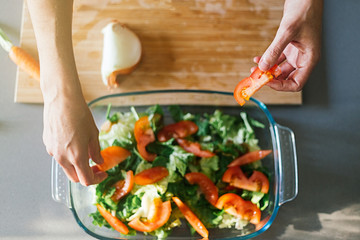 Woman making a healthy salad in a glass recipient