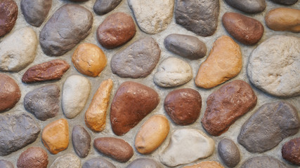 stone wall texture of bright smooth natural stones of different colors. masonry construction