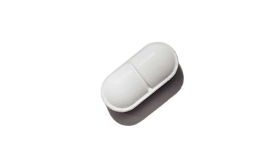 Close-up of white pill isolated on white background.