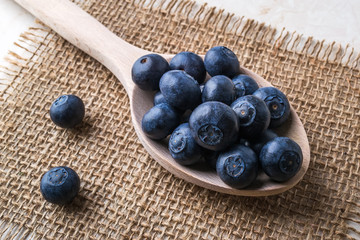 Ripe juicy blueberries in a large wooden spoon on a  sackcloth napkin. Fruits and berries, vegetarian and healthy eating. Super food. Ready to eat.