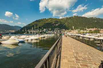 Obraz premium Como, WŁOCHY - 4 sierpnia 2019: Marina nad jeziorem Como w centrum pięknego włoskiego miasta Como. Ciepły, słoneczny letni dzień w bardzo popularnym miejscu na wakacje