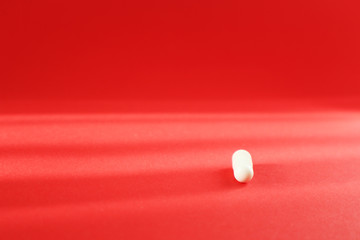 White pill on red background. Top view with copy space. Medicine concept.