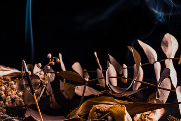 Stick holder and incense stick with leaves and flowers on black background