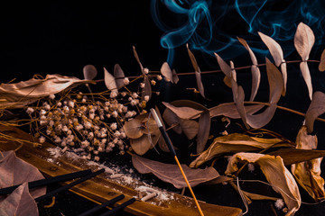 Stick holder and incense stick with leaves and flowers on black background