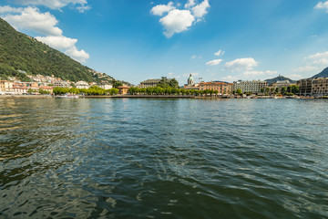 Como, ITALY - August 4, 2019: Apartments, villas, hotels on the green forested mountainsides near Lake Como. Beautiful Italian Como city. Warm sunny summer day in very popular holiday destination