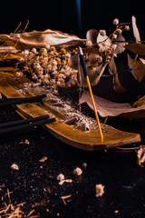 Stick holder and incense stick with leaves and flowers on black background