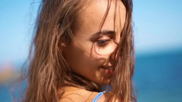 Close Up slow motion Beautiful tanned woman Walking On Beach Looking Back At Camera Smiling wind blowing hair