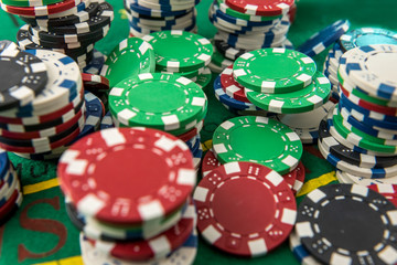 Black white red blue green casino chips stacks on green poker table. Betting club and gamble.