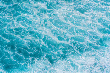 The azure surface of the ocean. Waves break at the shore. Texture of the water surface near the shore above the coral reef. Aerial photography of water.