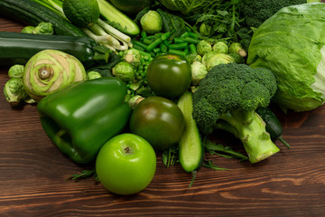 Collection of green vegetables produce on dark background, broccolini, avocado, squash, chilli, grapes part of flat lay overhead set