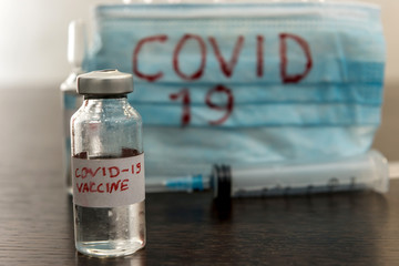 COVID-19 coronavirus ampoule with a vaccine, infected blood in the syringe, medical mask. Dangerous diseases and viruses
