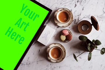 Placeholder for poster product photo. Frame, macarons, coffee, plant and a box of matches with homemade logo against white marble. Green screen template.