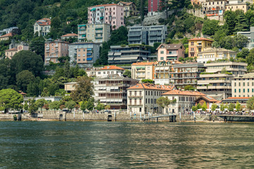 Como, ITALY - August 4, 2019: Apartments, villas, hotels on the green forested mountainsides near Lake Como. Beautiful Italian Como city. Warm sunny summer day in very popular holiday destination