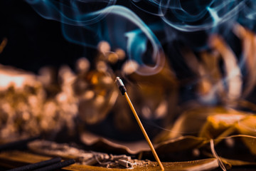 Stick holder and incense stick with leaves and flowers on black background