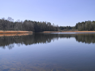 Panoramatic and scenic landscape Picture of the lake in the middle of nowhere in Czech republic taken in sunny spring afternoon in early sunset. Clear silent countryside to spend holiday there.