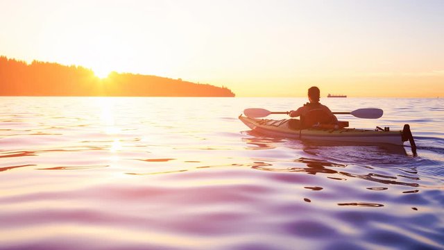 Cinemagraph Continuous Loop Animation. Woman on a sea kayak is paddling in the ocean during a colorful and vibrant sunset. Jericho, Vancouver, British Columbia, Canada. Concept: Adventure, Holiday