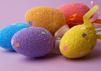 multi-colored decorative Easter eggs on sticks on a purple background, festive backdrop
