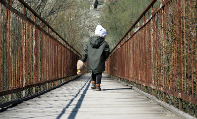 boy on a bridge with a wooden deck and rusty metal railing