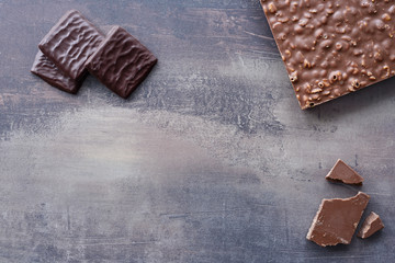 Top view of different types of chocolates - dark and milk. Chocolate bar with nut filling. Sweets on marble table background.