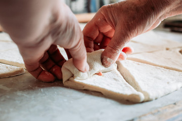 Female hand rolling raw, unbaked croissant roll.