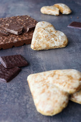 Verticl photo of different types of chocolate and gingerbread heart. Sweets on marble table background.