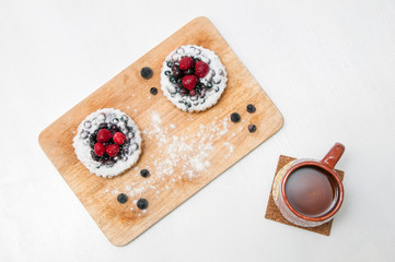 Breakfast at home. Two berry pies on a wooden tray and a cup of tea on a white background.