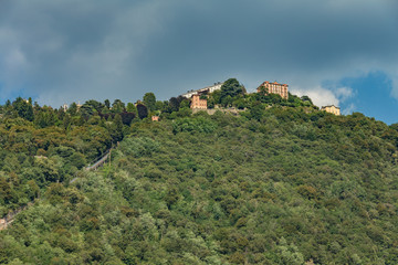 Obraz premium Como, ITALY - August 4, 2019: Apartments, villas, hotels on the green forested mountainsides near Lake Como. Beautiful Italian Como city. Warm sunny summer day in very popular holiday destination