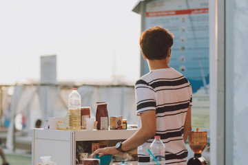 Young adult with dark hair selling products on outdoor market