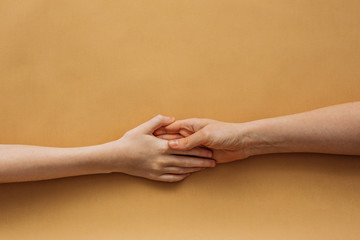 On a solid background, a woman's hand is holding a child's hand