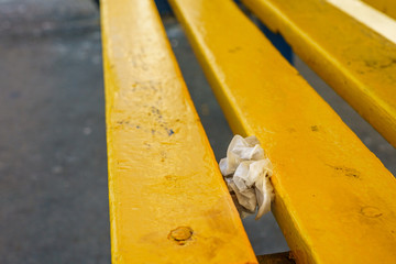 Pair of used nitrile medical gloves shoved in between slats on public seating during Coronavirus Covid-19 pandemic