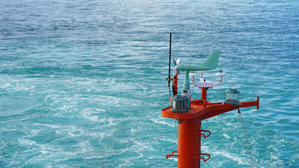 Bright weather vane on a background of blue ocean water. windmill for measuring wind strength and...