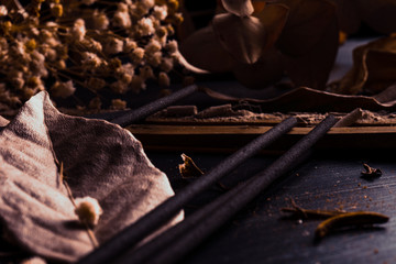 Stick holder and incense stick with leaves and flowers on black background