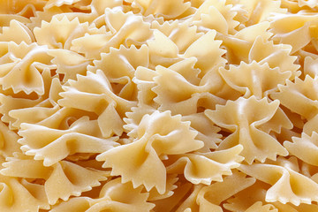 Variety of types and shapes of Italian pasta. Dry pasta background. A portion of Farfalle bows pasta isolated on white . Heap of bow tie pasta isolated on white background.