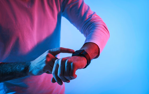 Man in neon with smartwatch on hand