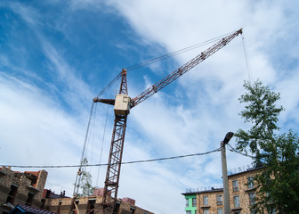 Provincial poor city. Against the background of a blue sky with white clouds, a tower crane is visible.