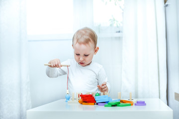 baby boy plays with educational toy. toddler play with a wooden toys at home. Toddler play with a color educational toy. Child play at the table in the baby room. Child development. 