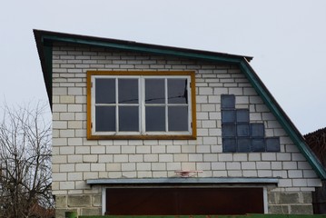 attic of a private white brick rural house with a large window against the sky