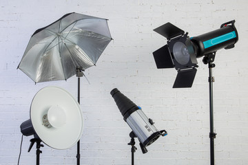 Large professional photo studio lamps on a white brick wall.