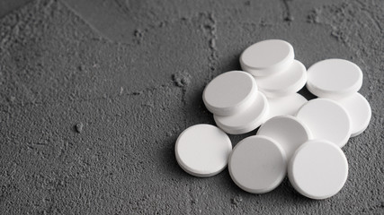 Bunch of white pills on gray background. Pile of the white tablets.