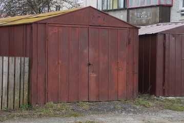 one red rusty iron garage with closed gates on the street