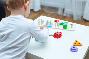 baby boy plays with educational toy. toddler play with a wooden toys at home. Toddler play with a color educational toy. Child play at the table in the baby room. Child development. 