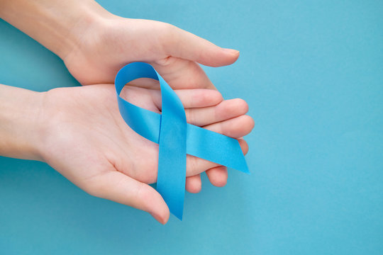 Blue symbolic tape on two hands - sclerosis, human trafficking, sexual slavery, colon cancer, chronic fatigue on a blue background