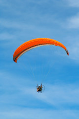 Parapente laranja isolado no céu de Salvador.