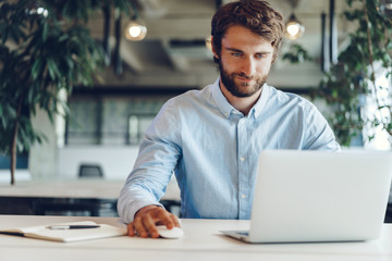 Businessman in shirt working on his laptop in an office. Open space office