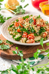 Tabbouleh salad - traditional Middle Eastern or Arabic cuisine. Levantine vegetarian salad with bulgur, quinoa, tomato, cucumber, parsley and lemon juice. Tabbouleh with bulgur closeup